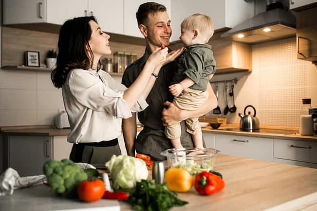 Be more productive - parents holding their toddler son in the kitchen