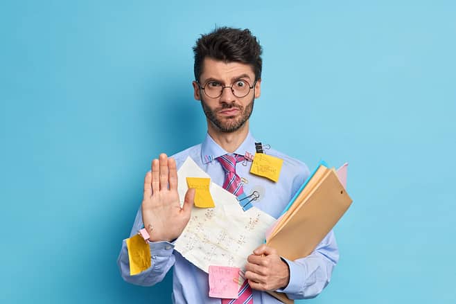 be more productive - man with papers everyone looking stressed holding up his hand as if to say "no"